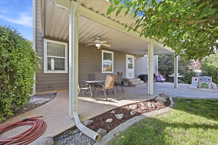 Expansive covered patio featuring dual ceiling fans, concrete flooring, and a dedicated walkway