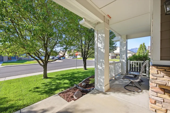 Covered front porch with white columns, balusters, and a mountain backdrop