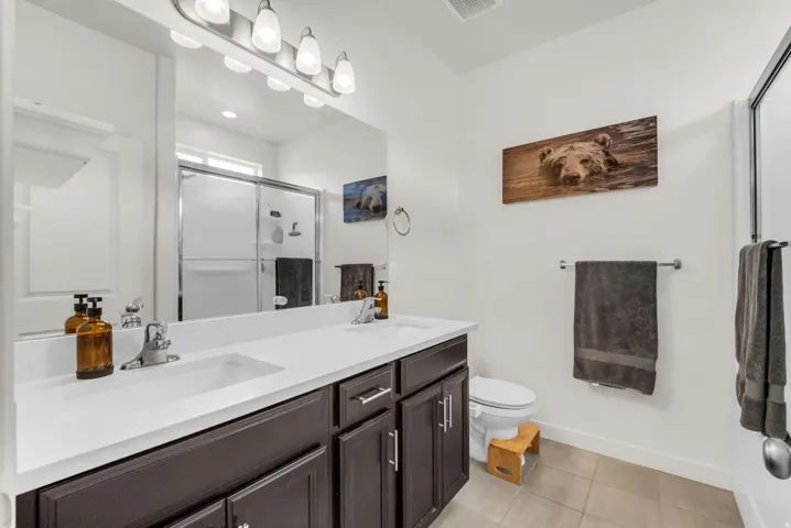Dual sink vanity with dark wood cabinetry, white countertops, and chrome fixtures