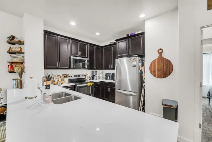 Kitchen featuring dark wood cabinetry, white countertops, stainless steel appliances, and recessed lighting