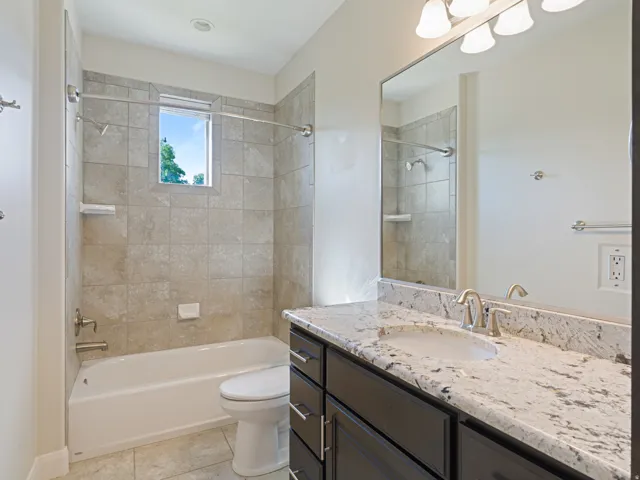 Full bathroom with a tub/shower combination, tiled surround, and window