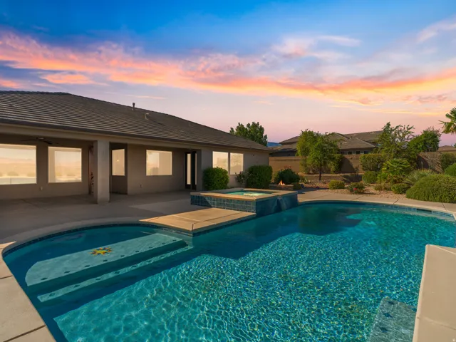 Expansive backyard featuring a blue-tiled swimming pool with integrated spa and a covered patio