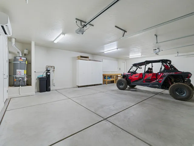 Spacious garage featuring a concrete floor, built-in cabinetry, and a water heater