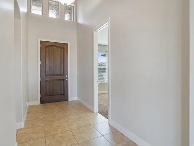 Entryway with tile flooring, a dark wood-paneled door, and transom windows