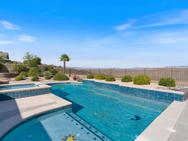 Outdoor pool and elevated spa featuring blue mosaic tile accents