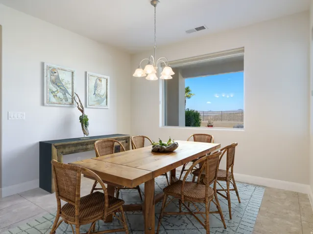Spacious dining area featuring a large picture window, a cream-toned chandelier, and light-toned walls