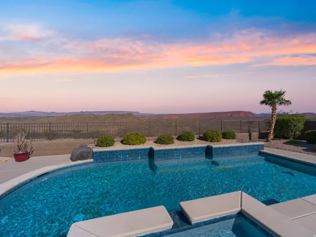 Curved swimming pool featuring blue tile accents and integrated seating