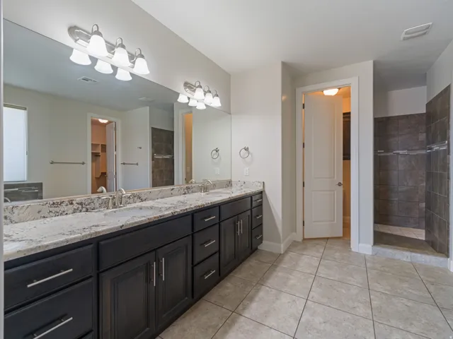 Extended double vanity featuring a light-toned stone countertop with dual undermount sinks and dark wood-finish cabinetry