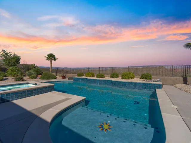 Resort-style pool area featuring a built-in spa, blue mosaic tile accents, and integrated water features