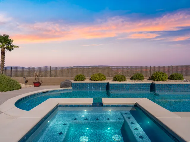 Resort-style pool area featuring a built-in spa, integrated waterfall features, and blue mosaic tile finishes