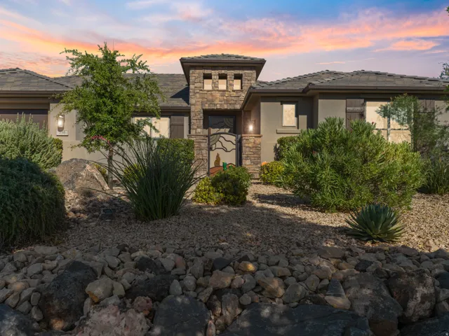 Stone and stucco exterior with a tiled roof, featuring a decorative metal gate and sconce lighting