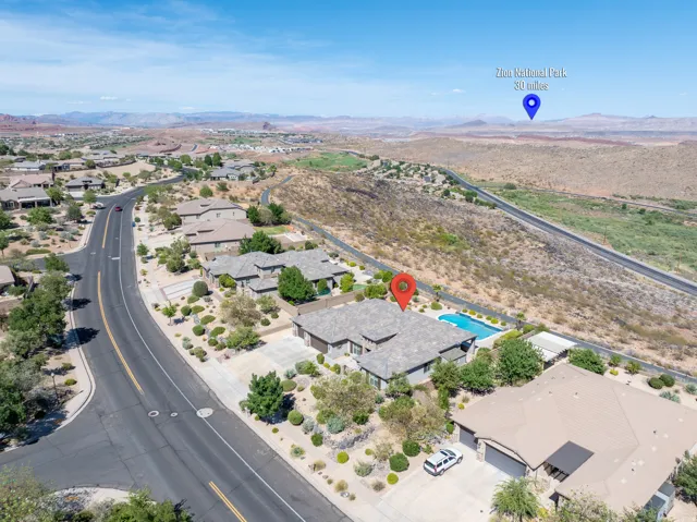 Expansive property featuring a private swimming pool, mature desert landscaping, multi-car driveway, and a tiled roof, all situated within a residential community with distant mountain ranges