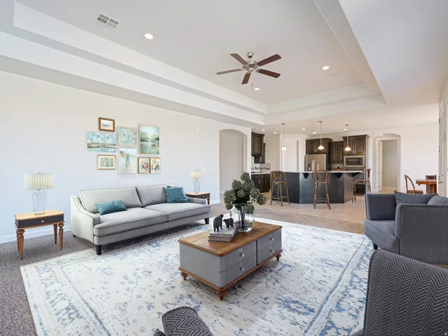 Expansive living area featuring a tray ceiling, recessed lighting, and a ceiling fan
