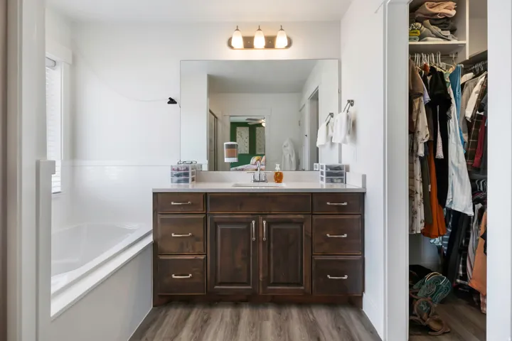 Built-in vanity with wood-finish cabinetry, light-toned countertop, and undermount sink