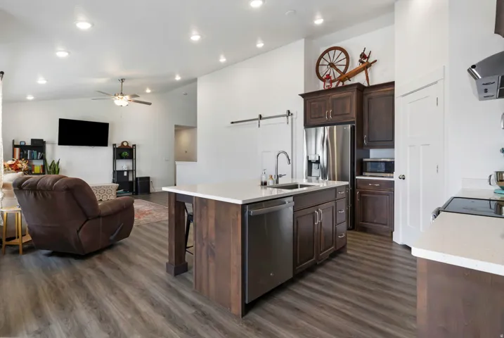 Open-concept living space featuring wood-finish flooring, recessed lighting, and a vaulted ceiling