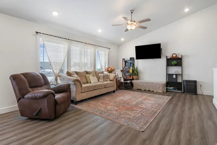Spacious living area featuring wood-finish flooring, a ceiling fan, and recessed lighting
