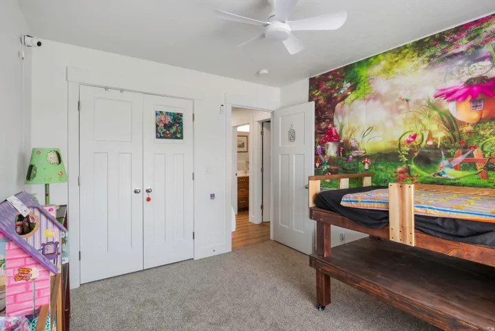 Carpeted flooring with white trim, a white ceiling fan, and a white interior door with paneling