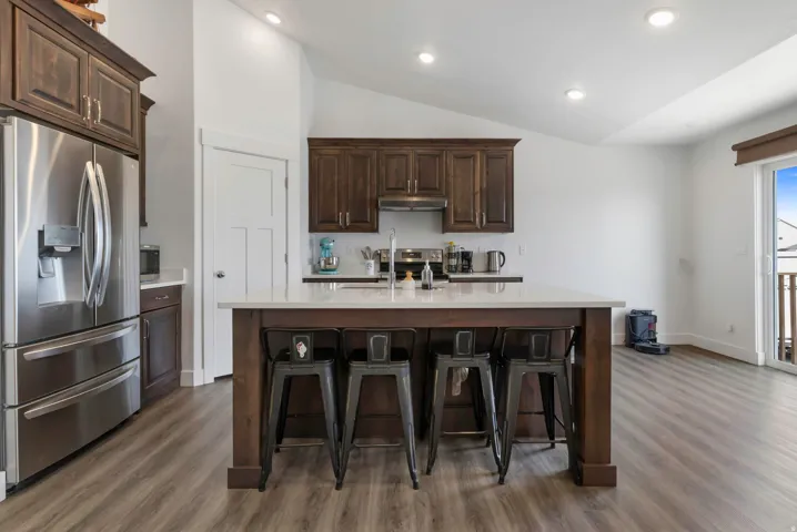 Kitchen featuring dark wood-finish cabinetry, stainless steel appliances, a center island with light-toned countertops, and recessed lighting