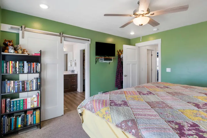 Recessed lighting, ceiling fan with light fixture, white interior doors, barn door entry to bath, wood-finish flooring in bath