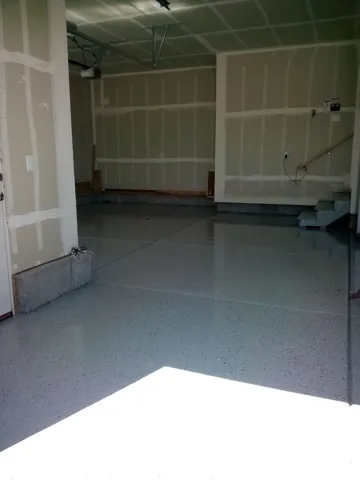 Expansive garage with unfinished walls, exposed ceiling joists, and a multi-level floor