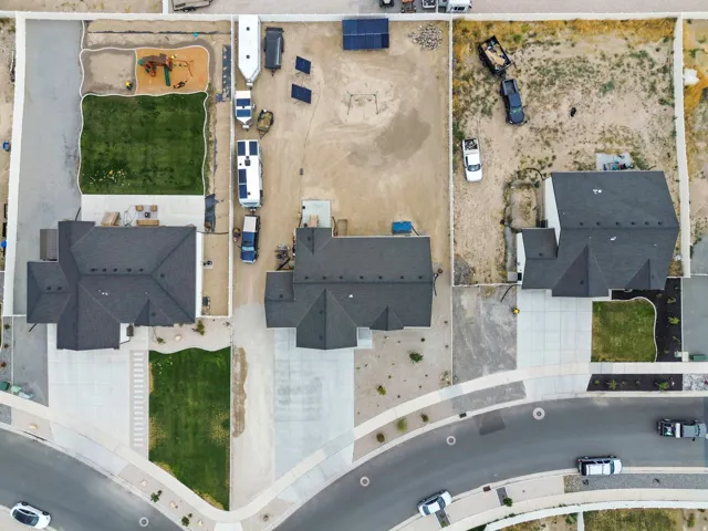 Aerial perspective showcasing three properties, each featuring a dark-shingled roof and concrete driveways