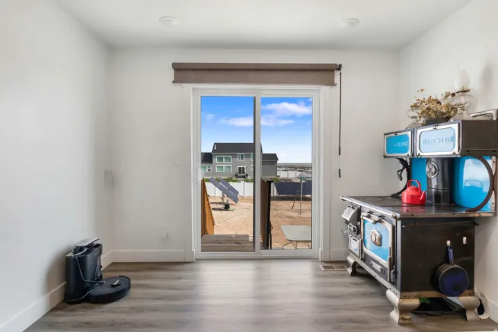Sliding glass door leading to exterior, wood-finish flooring, recessed lighting, and bright white walls