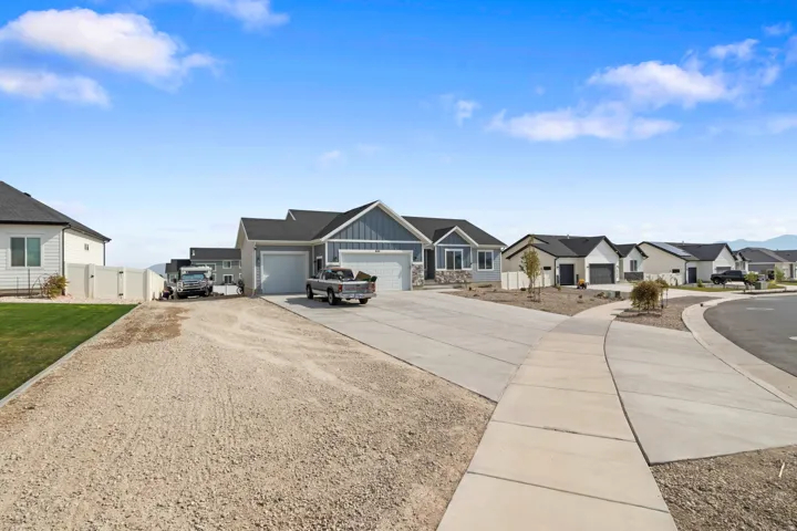 Contemporary ranch-style home featuring a two-car garage, partial stone facade, and gray siding