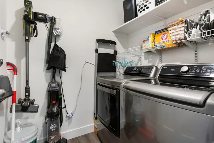 Dedicated utility area featuring stainless steel appliances, white shelving, and wood-finish flooring