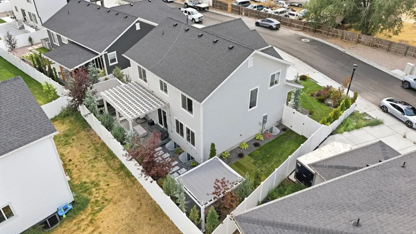 Rear exterior featuring a white pergola, patio with paver stones, and landscaped gardens