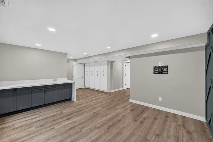 Open concept room featuring wood-finish flooring, recessed lighting, and a built-in counter with dark cabinetry and a light-colored countertop