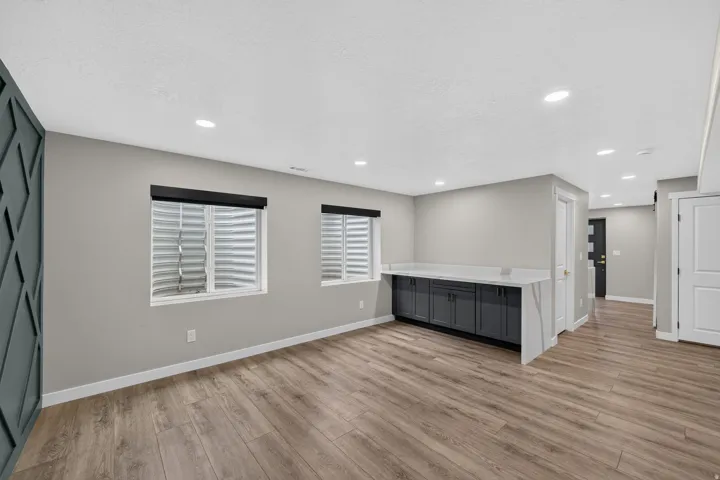 Spacious room featuring wood-finish flooring, recessed lighting, and a built-in cabinetry unit with a light-toned countertop