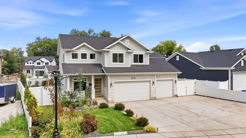 Two-story residence featuring light gray siding with white trim, a dark shingle roof, and stone-veneer accents