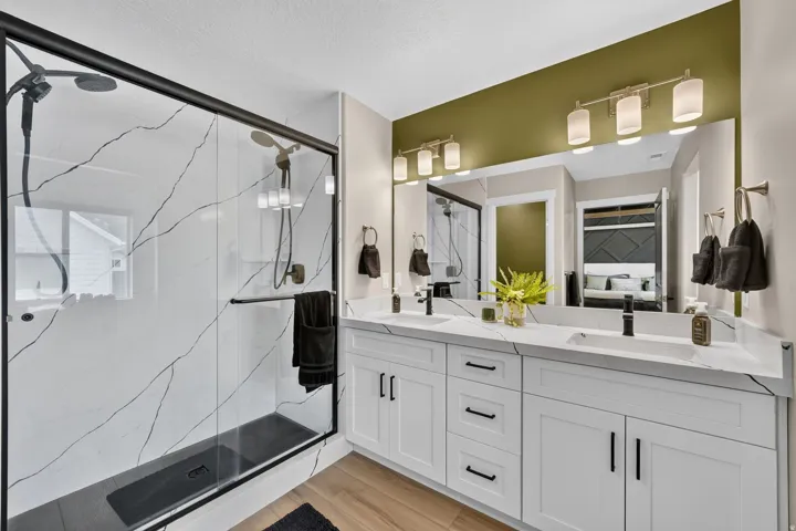 Modern bathroom featuring a spacious walk-in shower with black-framed glass enclosure, white marble-look tile, and a dark shower pan