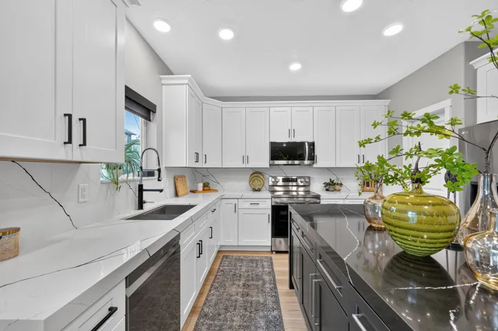 Modern kitchen featuring white shaker cabinetry, stainless steel appliances, and contrasting countertops