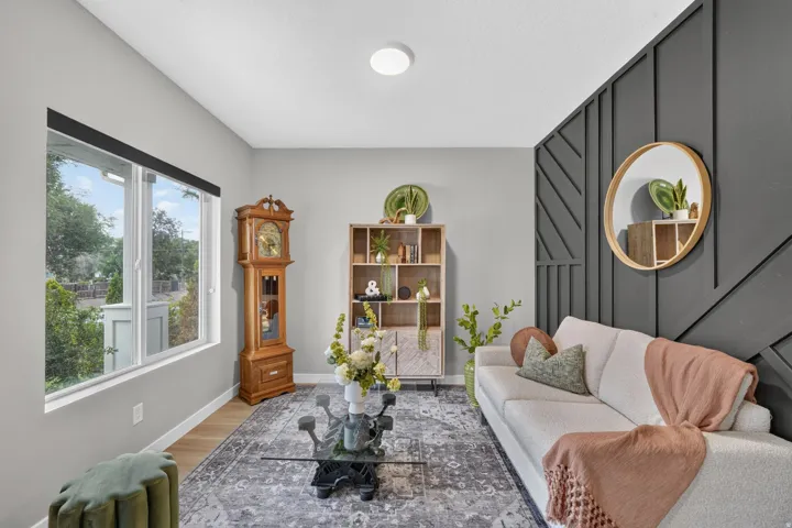 Accent wall with geometric paneling, natural light from a large window, light wood-finish flooring, and recessed ceiling lighting