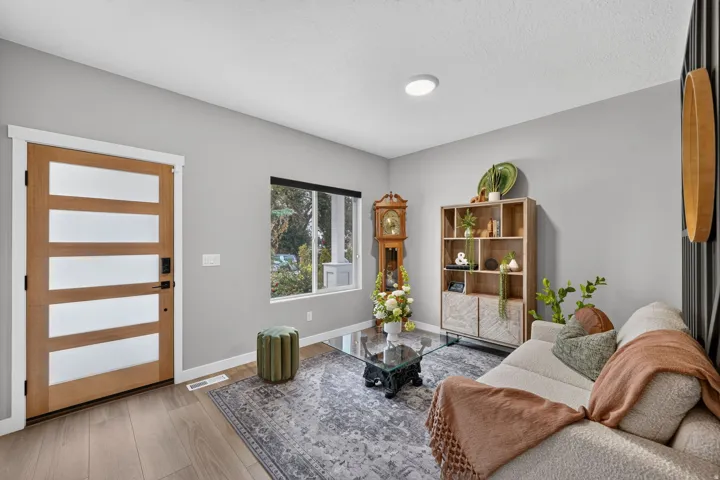 Wood-finish flooring throughout, featuring a contemporary front entry door with horizontal frosted glass panels and sleek black hardware