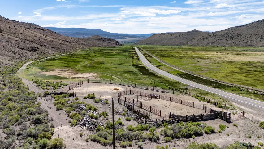 Expansive rural acreage featuring a livestock corral, a paved roadway, and natural desert vegetation