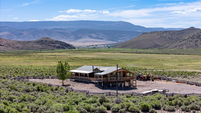 Elevated home featuring a wood-clad exterior, covered porch, and a gravel perimeter