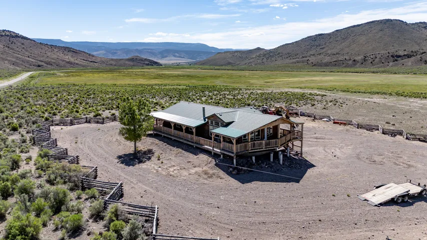 Ranch-style residence featuring a green metal roof, a full-length covered porch, and an elevated deck