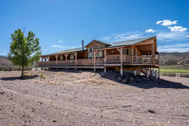 Elevated cabin-style residence featuring a full-length covered porch, natural wood siding, and a durable metal roof