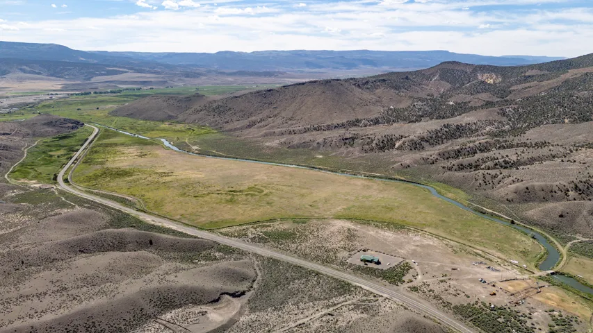 Expansive land parcel featuring a winding river, verdant fields, and distant mountain ranges