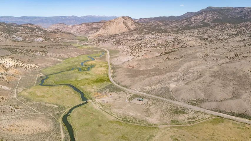 Expansive valley terrain featuring a meandering river system, bordering a paved roadway