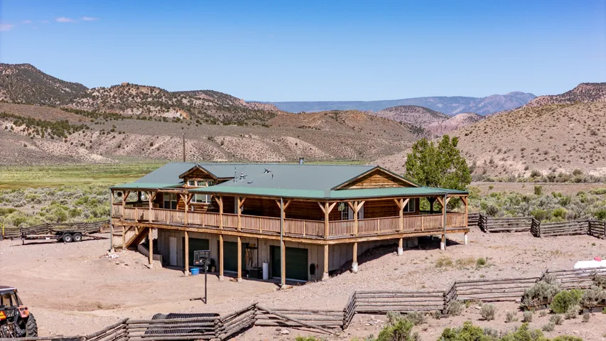 Rustic cabin-style residence featuring a wrap-around porch and a green metal roof
