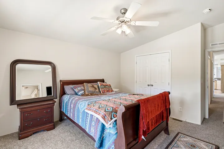Carpeted room featuring a white ceiling fan with integrated lighting, bi-fold closet doors, and light-toned wall finishes