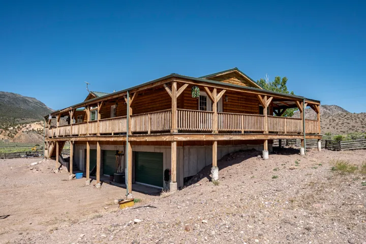 Rustic log-cabin style exterior with a wrap-around wooden deck and covered porch
