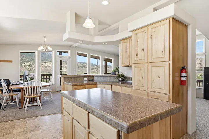 Kitchen island with a laminate countertop, light wood cabinetry, recessed lighting, and a multi-light chandelier