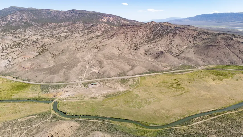 Expansive land parcel with a winding river feature, surrounded by varied terrain and distant mountains