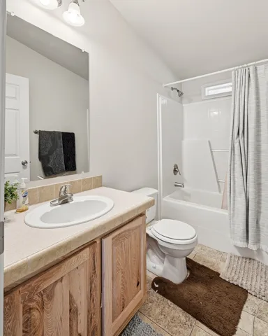 Bathroom featuring a single vanity with wood cabinetry, an oval sink, and a light-toned countertop
