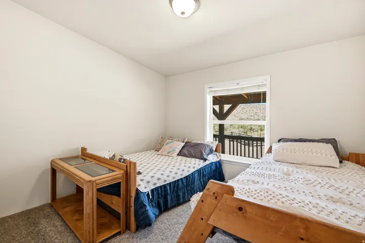 Room featuring light neutral walls, a window with exterior deck access, and gray carpet flooring
