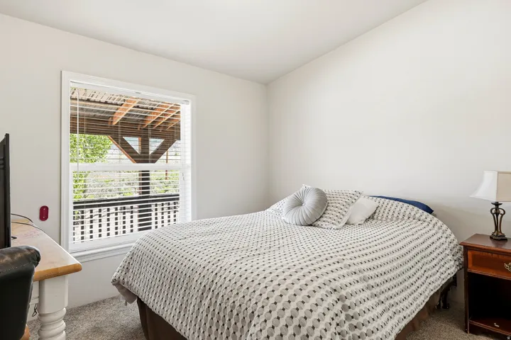 Window with white blinds overlooking an exterior wood-frame deck with black balusters
